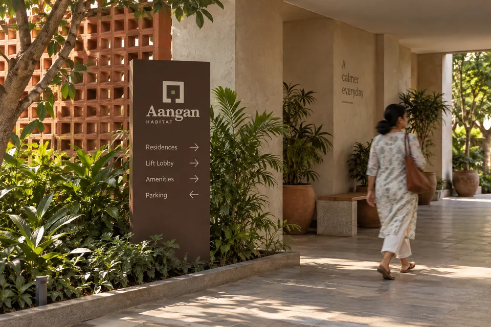 Natural-scale courtyard arrival with Aangan Habitat wayfinding and an Indian adult passing through the frame.