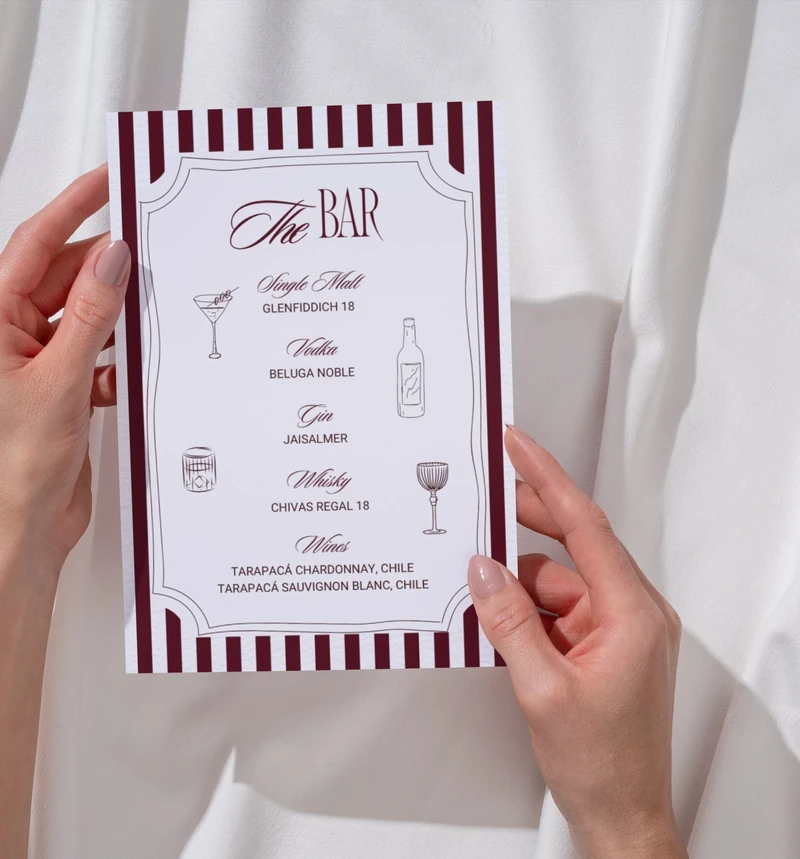 Photograph of a hand holding the burgundy The Bar menu.