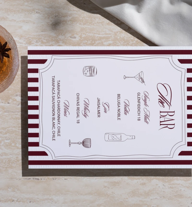 Photograph of the burgundy The Bar menu resting on a stone tabletop.