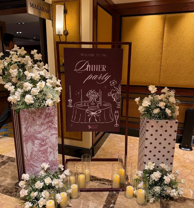 Photograph of the arrival easel surrounded by flowers and candles at the venue entrance.